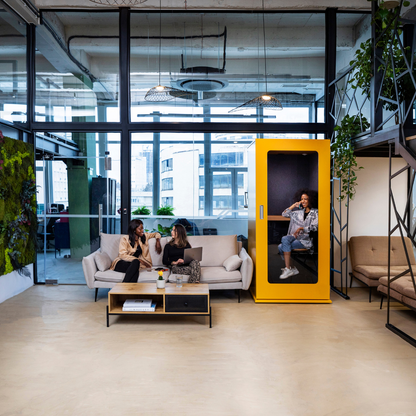 Meavo Soho pod in yellow rendered in an office with 3 people in the image, one inside the pod, two outside the pod. 